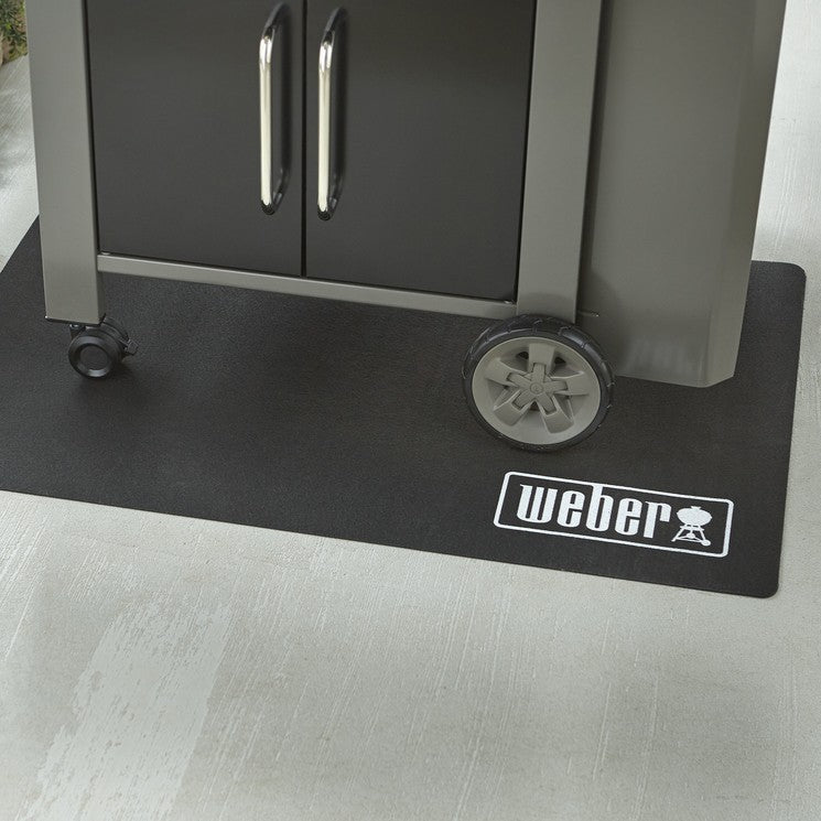 Weber grill on a black mat with a patio background