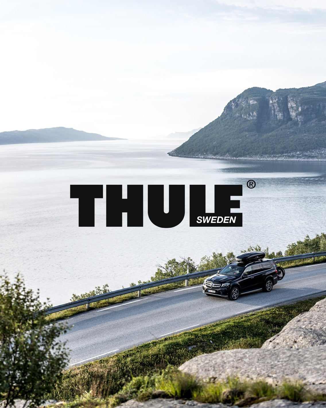 Car driving on a scenic road with mountains and water in the background, featuring the Thule Sweden logo.
