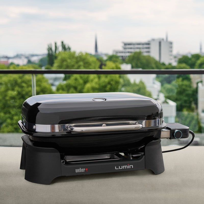 Black grill with 'Lumin' branding on a balcony with a cityscape background