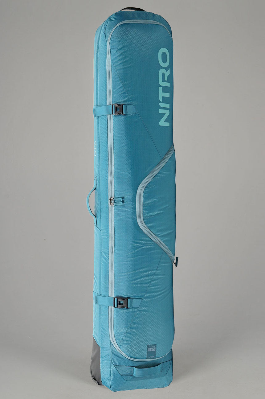 A light blue Nitro snowboard bag standing vertically against a neutral gray background. The bag features the brand name 'NITRO' printed vertically in a matching light blue on the upper right side, with silver-gray piping details and black buckle closures.