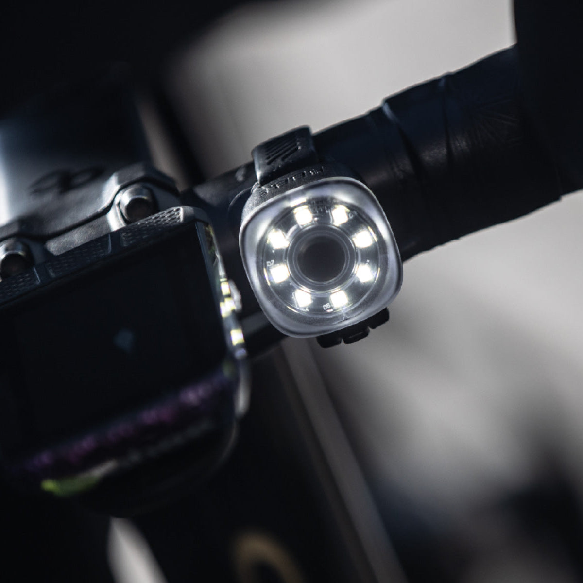 Close-up of a bicycle light attached to a handlebar with a blurred background
