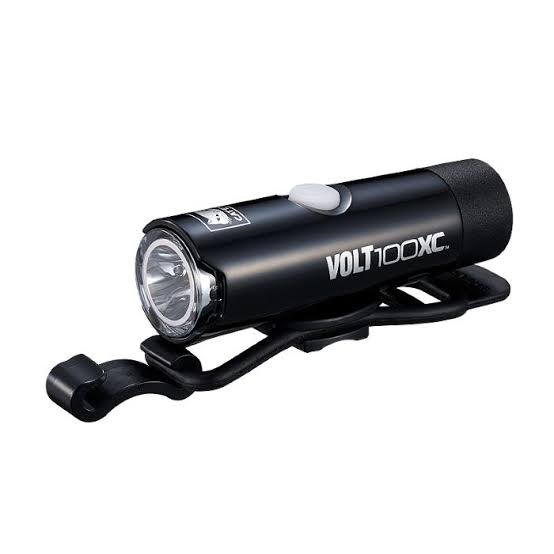 A black Volt 100XC bicycle headlight with an integrated black clip, featuring a silver button and clear lens, shown against a plain white background.