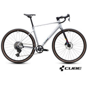 A silver and black CUBE gravel bicycle with drop handlebars, disc brakes, and knobby tires, shown from a side profile on a white background with a CUBE logo at the bottom right.