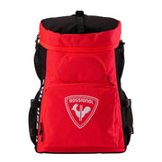 A red and black Rossignol backpack with a white embroidered club crest on the front pocket, shown against a light gray studio background.