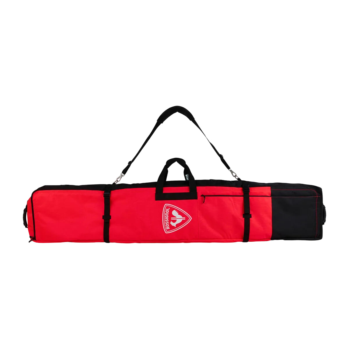 A red and black long sports bag with a shoulder strap and top handle, featuring a shield-shaped logo on the front, photographed on a light gray studio background.
