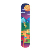 A snowboard with a vibrant, colorful graphic print featuring a cartoon dinosaur, mountains, a large orange sun, and a purple night sky, shown against a neutral gray background.