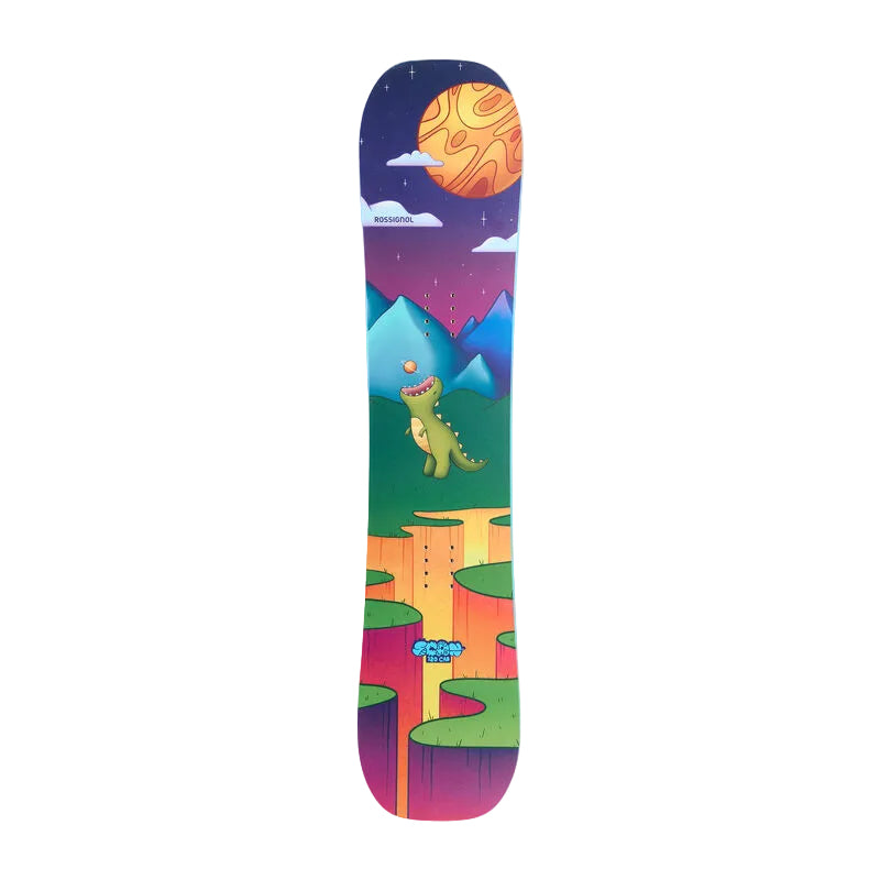 A snowboard with a vibrant, colorful graphic print featuring a cartoon dinosaur, mountains, a large orange sun, and a purple night sky, shown against a neutral gray background.